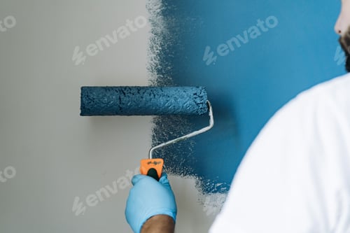 Preview: caucasian bearded man painting wall with paint roller. Painting apartment, renovating home