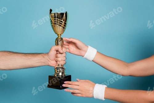 Preview: cropped view of man giving golden trophy to female champion on blue