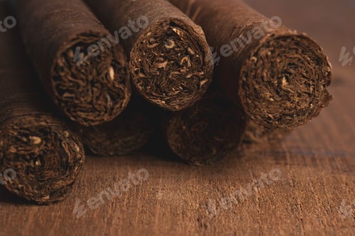 Preview: Selective focus of rolled cigars on a brown wooden table