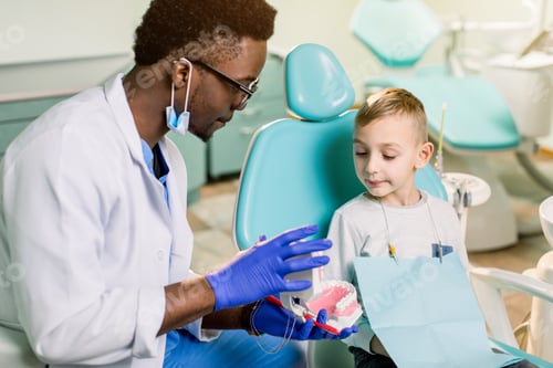 Preview: African American Man dentist in a uniform. Plastic jaw in the dentist's office.