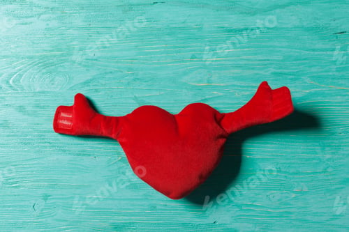 Preview: Red heart with hands on a blue wooden surface in a simple arrangement
