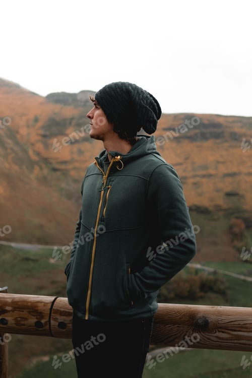 Preview: Young Man in Green Jacket Observing Scenic Mountain Landscape