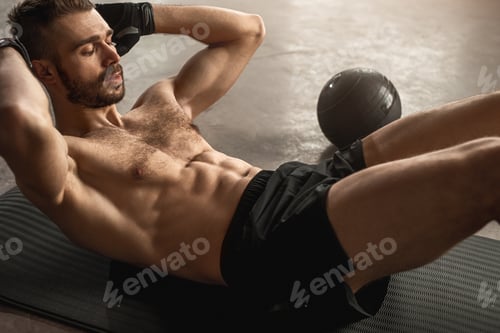 Preview: Muscular sportsman doing abs exercise in gym