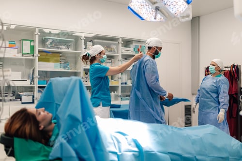 Preview: Medical team in sterile gown and surgical mask prepping in an OR.
