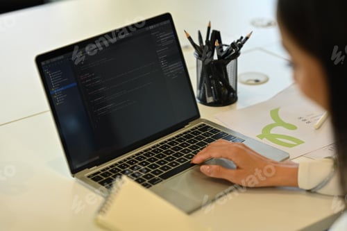 Preview: Cropped shot of female developer working with coded data on computer screen at her office.