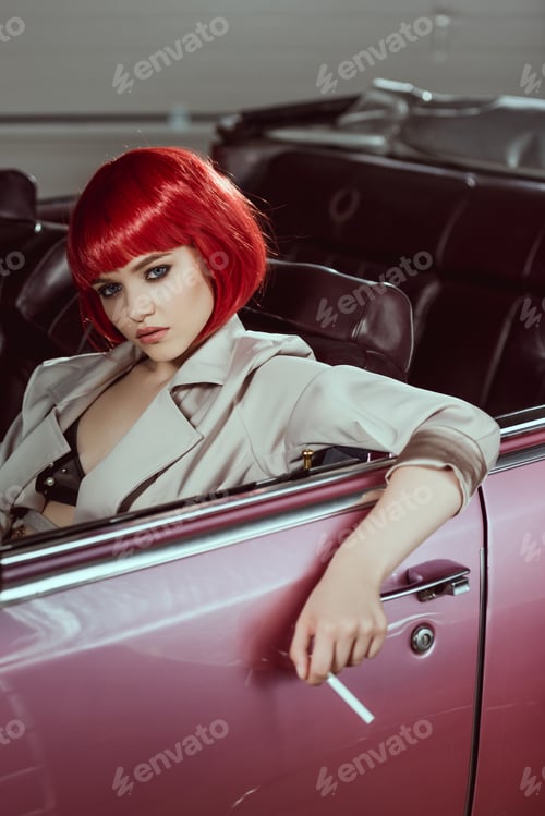 Preview: beautiful young woman in red wig holding cigarette and sitting in vintage car