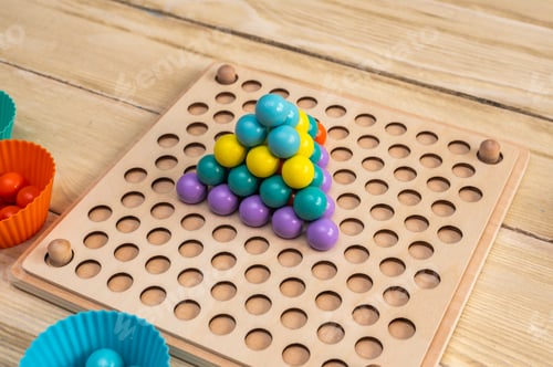 Preview: colorful ball puzzle stacked in pyramid shape on board,