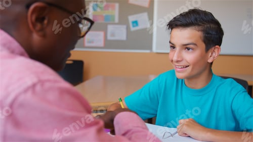 Preview: High School Tutor Giving Male Student One To One Tuition At Desk