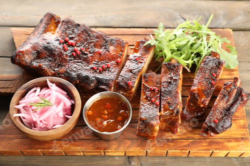 Preview: Delicious spare ribs, onion, sauce and arugula on wooden table