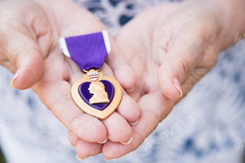 Visualização: Mulher sênior segurando a medalha militar de coração roxo nas mãos.