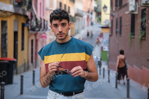 Preview: Young caucasian man with long false nails posing with his sunglasses at street.