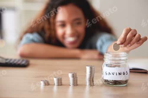 Preview: Unknown mixed race woman calculating and stacking a variety of coins and depositing them into a sav