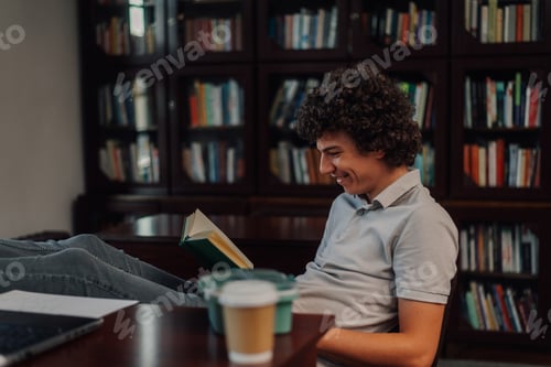 Preview: Happy student smiling and reading a book in the library