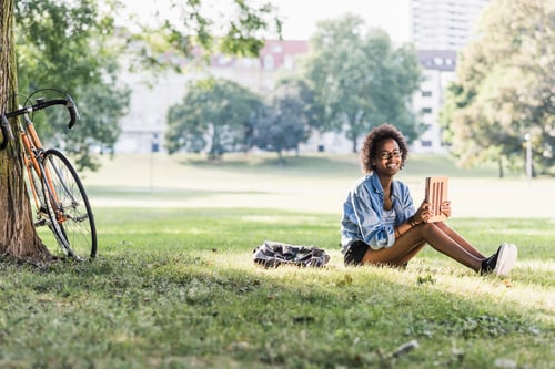 Preview: Smiling young woman resting in park with tablet