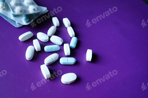 Preview: Close up of pills spilling on purple desk
