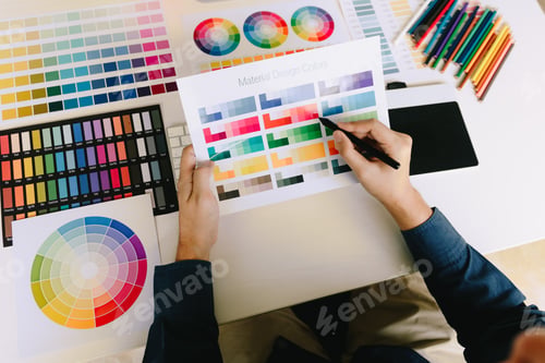 Preview: Young people holding pen pointing at color sheet in business office.