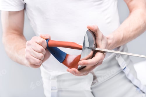Preview: Close-up partial view of young man professional fencer holding rapier isolated on white