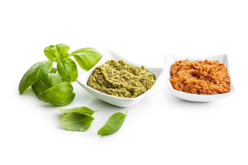 Preview: Green basil and red tomato pesto dip sauce and basil leaves.