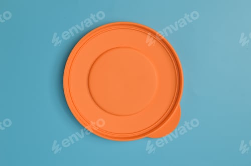 Preview: An orange plastic lid isolated on a blue background
