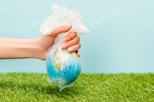 Preview: Cropped view of woman holding plastic bag with globe on green and blue, global warming concept