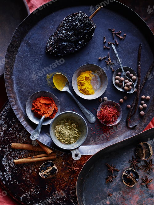 Preview: Spoons with spices on a dark, rustic cooking surface.