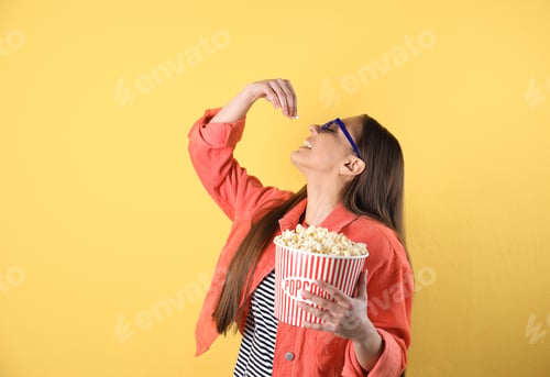 Preview: Young woman with 3D glasses eating tasty popcorn on color background