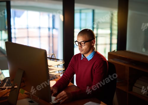 Preview: Dedicated and diligent. High angle shot of a handsome young man working late in his office.