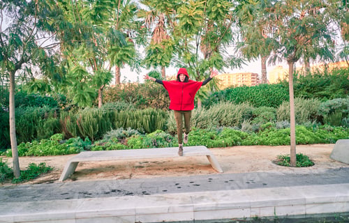 Preview: Young caucasian female with a red jacket jumping in a park