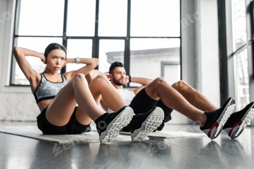 Preview: young couple doing abs exercise on yoga mats in gym