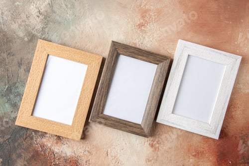 Preview: Above view of three wooden photo frames in different sizes hung on side by side on mix color wall