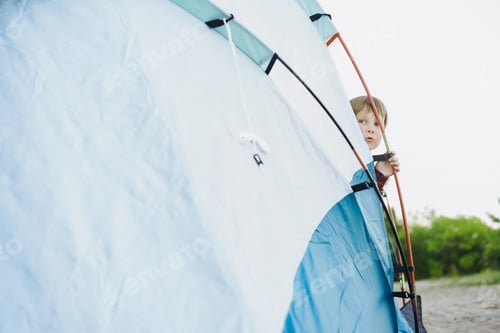 Preview: cute little caucasian boy looking out from touristic tent. Family camping concept