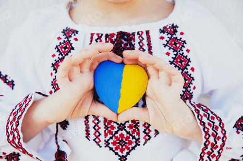Preview: Girl in embroidery or embroidered shirt hold heart shape with Ukrane flag