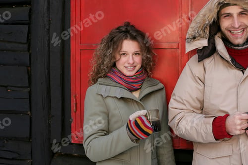 Preview: Smiling couple enjoying a chilly day outside a red door