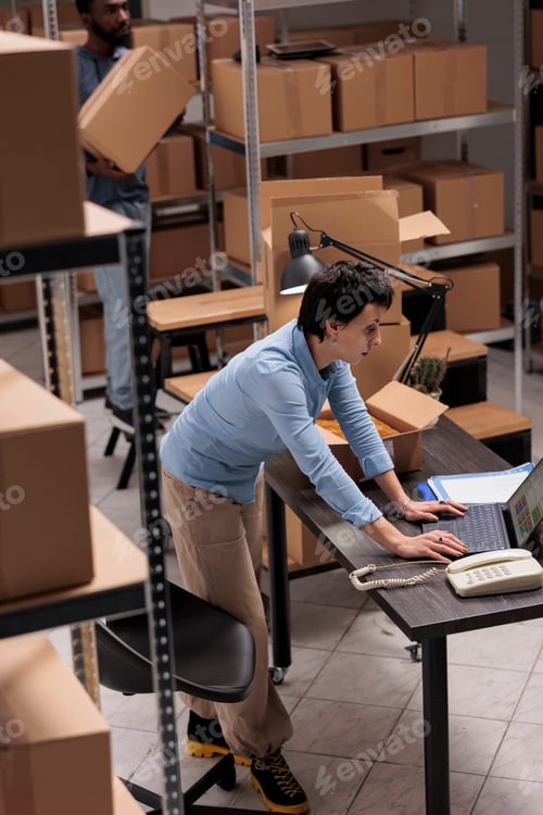 Preview: Warehouse manager checking shipping details on laptop computer before start packing customers orders