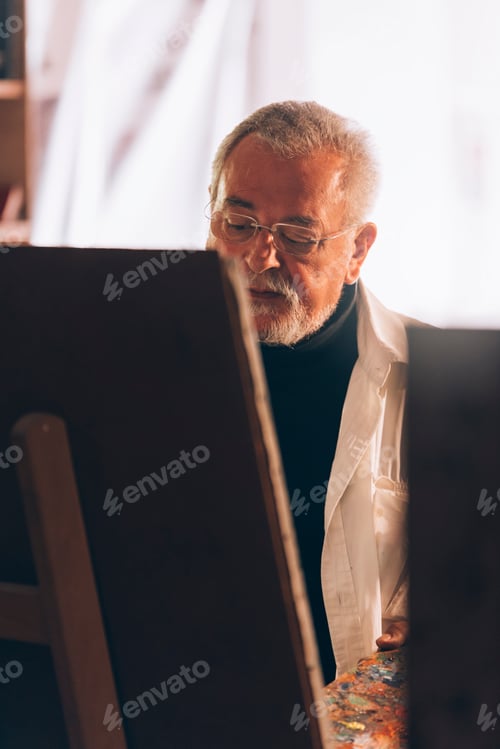 Preview: Old man artist painting oils in his studio.