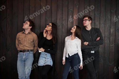 Preview: Youth stands against black wooden wall. Group of friends spending time together