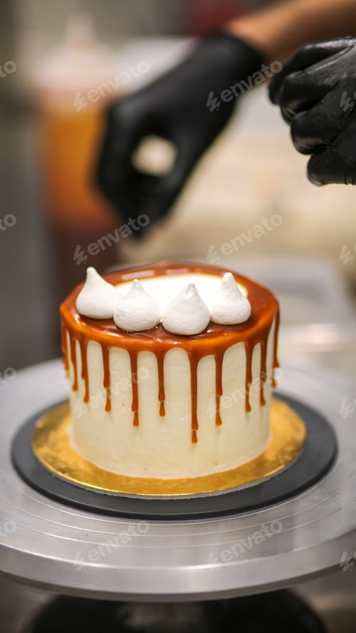 Preview: designer decorating frosted salty caramel icing cake with white meringue twirls