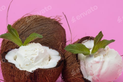 Preview: Vanilla ice cream balls in fresh coconut halves decorated with mint leaves on a pink background