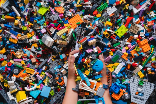 Preview: Colorful background of mixed plastic bricks toys with children's hands.