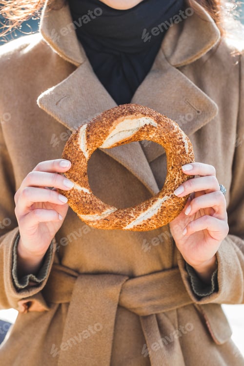Preview: Beautiful woman holds a traditional Turkish simit in hands and wants to eat it