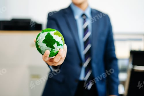 Preview: Businessman in suit holding a green earth model, symbolizing global sustainability,