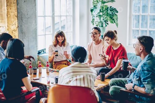 Preview: Cheerful multiethnic people playing board game in flat
