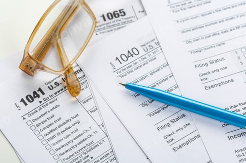 Preview: Filing taxes with forms, glasses, and a blue pen on a table in a home office space