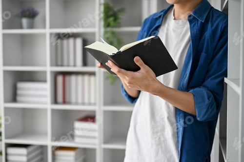 Preview: Close up view of college student reading book, lean against the book shelf.