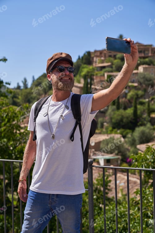 Preview: Middle aged man taking selfie on smartphone in old city