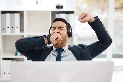 Preview: Shot of a young male call center agent yawning while working in an office