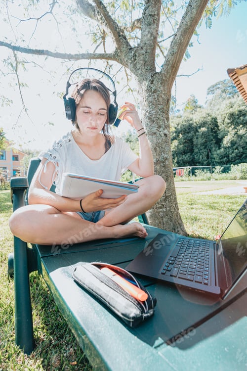 Preview: Young woman sitting on the garden smiling and studying for the university enjoys outdoor recreation