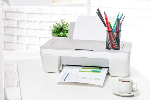 Preview: Printer on a desk prints documents while colorful pens stand in a holder near a cup of coffee in a