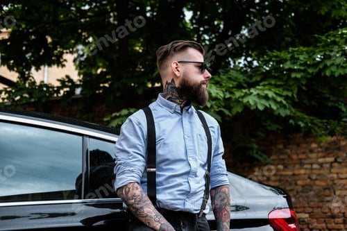 Preview: Attractive bearded man is leaning on his car.