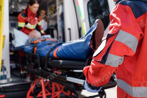 Preview: Selective focus of paramedic in uniform carrying stretcher with patient in ambulance ca outdoors